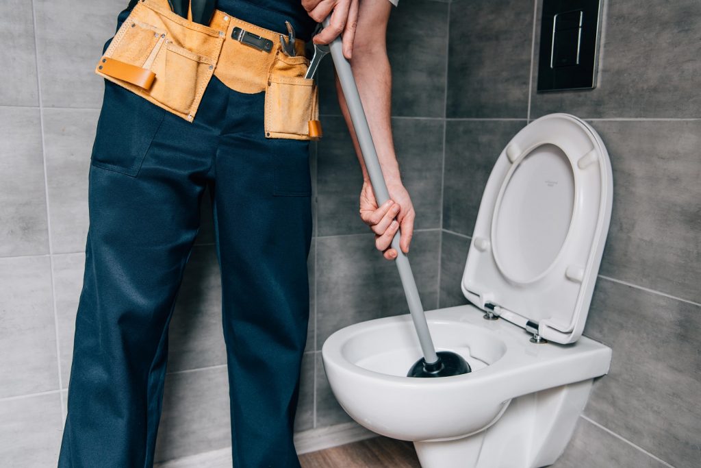 A plumber plunging the toilet